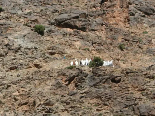 Eine Gruppe von Berber-Algeriern in traditioneller Kleidung wandert auf einem felsigen Hang.