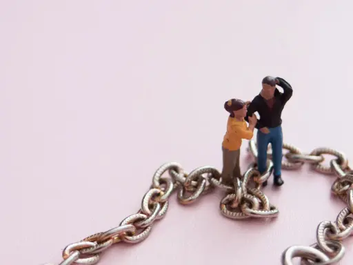 Figuras de pareja unidas por una cadena, simbolizando la codependencia de pareja.