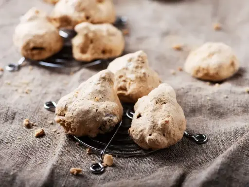 Biscotti meringati, dall'aspetto rustico ma dal sapore delizioso, noti come "brutti ma buoni", su una griglia.