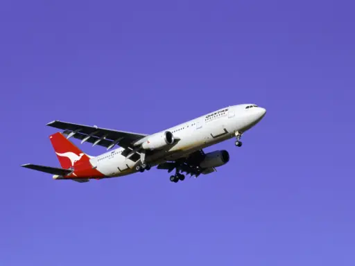 Samolot Qantas z charakterystycznym kangurem na ogonie, symbolizujący najbezpieczniejsze linie lotnicze, leci na tle błękitnego nieba.