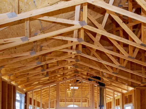Structure complexe de charpente en bois, avec des fermes et des poutres formant un contreventement bois solide pour une nouvelle construction.