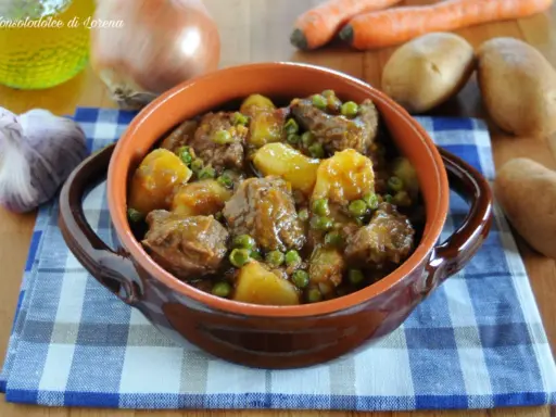 Un saporito spezzatino con patate e piselli, servito in una ciotola di terracotta, con ingredienti freschi sullo sfondo.