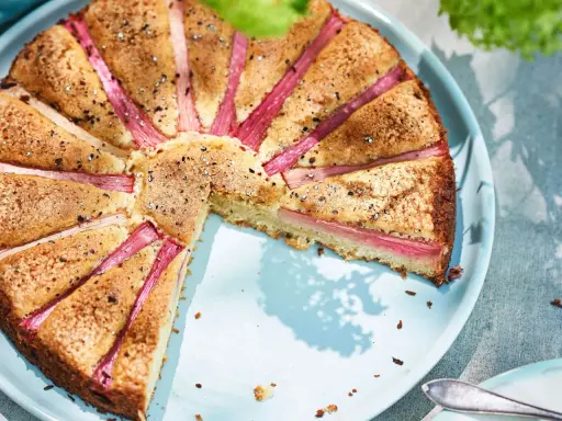 En saftig rabarberkaka med vackert arrangerade rabarberbitar, strödd med socker och kanel. Perfekt för en fika utomhus.