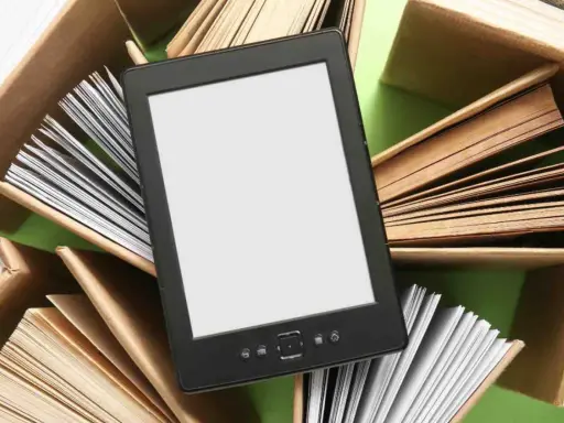 Un e-reader con schermo bianco è circondato da libri aperti, pronti per essere letti.