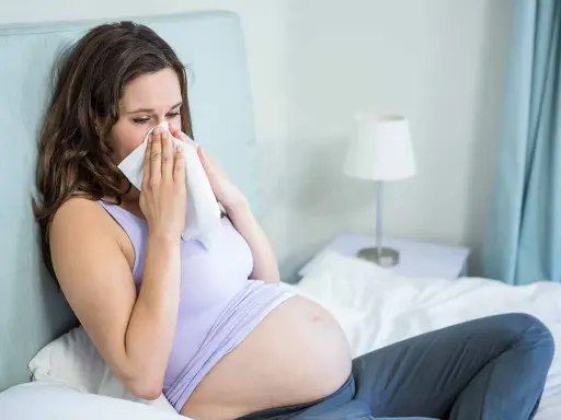 Donna incinta con raffreddore, cerca sollievo con un fazzoletto. La scelta di un antistaminico in gravidanza richiede attenzione.