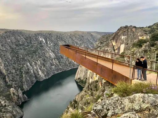 Pareja admira el paisaje desde el mirador del fraile, una pasarela metálica que se adentra en un cañón con un río.
