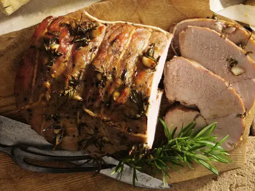 Pieczona jagnięcina co to? Soczysty, aromatyczny kawałek mięsa z rozmarynem i czosnkiem, pokrojony w plastry, gotowy do podania.