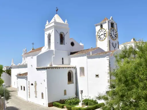 Weiße Kirche mit Glockenturm und Uhr im Herzen der tavira altstadt.