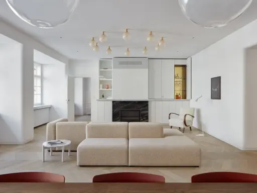 Un moderno sofá en medio del salón, con chimenea y estanterías integradas.