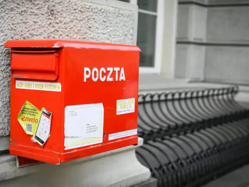 Czerwona skrzynka pocztowa z napisem "POCZTA". Można tu wysłać paczkę za granicę, listy i inne przesyłki.