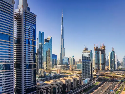 Nowoczesne wieżowce Dubaju, w tym Burj Khalifa, na tle błękitnego nieba. Widać autostrady i linie lotnicze Dubaj.