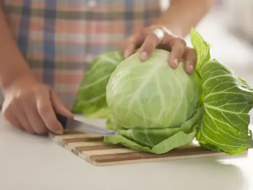 Ręce kroją kapustę na desce. Liście kapusty są gotowe na okłady z kapusty.