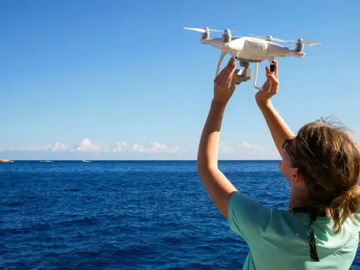 Frau hält Drohne über dem Meer in Kroatien, bereit zum Fliegen.
