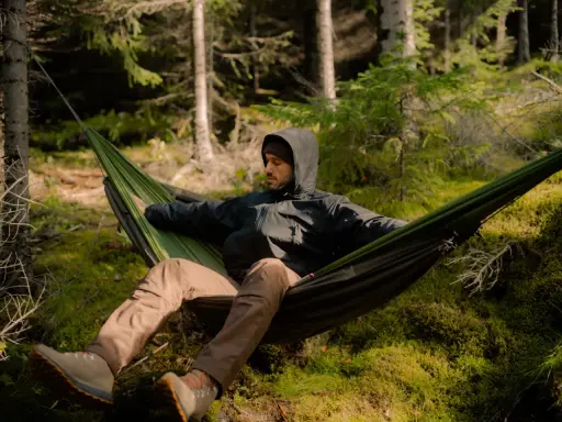 Mężczyzna w hamaku w lesie. To jest właśnie bushcraft – sztuka przetrwania i życia w zgodzie z naturą.