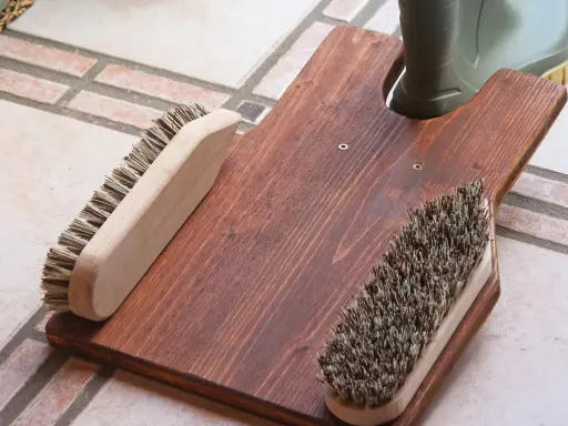 Selbstgebauter Bootsanker aus Holz mit zwei Bürsten und einem grünen Stiefel.