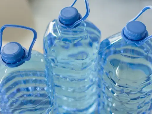 Trzy duże, niebieskie butelki z wodą, każda z uchwytem. Zastanawiasz się, ile może stać woda w plastikowej butelce po otwarciu?