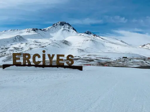 Zimowy krajobraz z napisem "ERCIYES" na tle ośnieżonych gór. Idealne miejsce na narty w Erciyes Ski Resort.