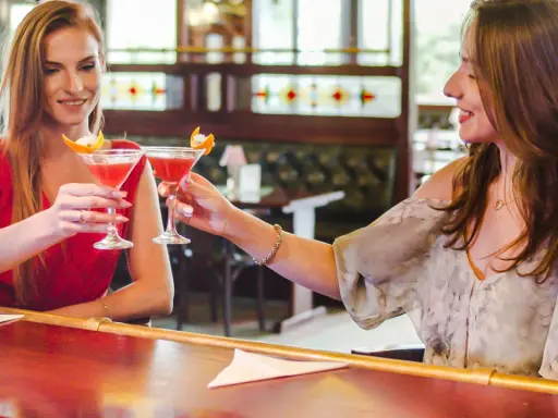 Dwie przyjaciółki wznoszą toast drinkami w barze. Idealny weekend z przyjaciółką!