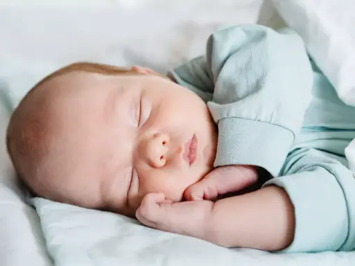 Un tierno recién nacido duerme plácidamente envuelto en mantas. Su carita serena y sus manitas descansan, disfrutando de un profundo sueño.