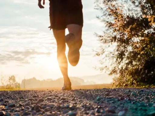 Gambe di un corridore su un sentiero sterrato al tramonto. Ottimo per bruciare calorie corsa 7 km/h.