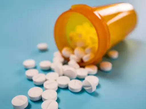 Białe tabletki rozsypane z pomarańczowego pojemnika. Toramide na co? Na ból, na gorączkę, na wszystko.