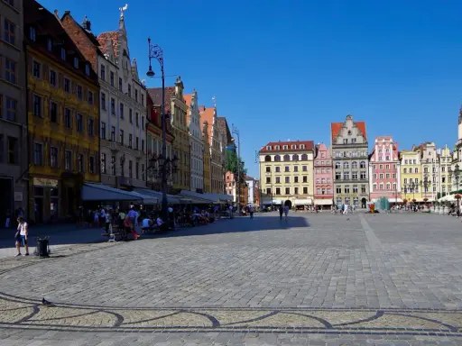 Kolorowy Rynek we Wrocławiu, idealne miejsce na jednodniowe wycieczki z Wrocławia. Ludzie spacerują, siedzą w kawiarniach, ciesząc się słońcem.