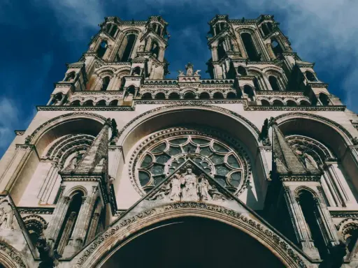 La **cathédrale de Laon**, majestueuse et imposante, se dresse sous un ciel bleu profond. Ses tours jumelles et sa rosace ornée captivent le regard.