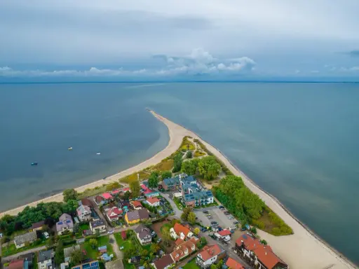 Malownicza miejscowość nad morzem z domkami i plażą, otoczona wodą.