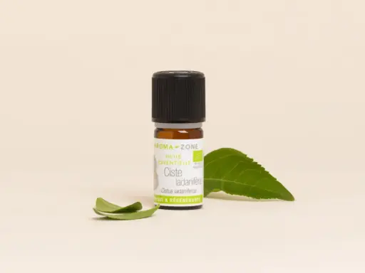 Flacon d'huile essentielle de ciste, aux vertus uniques et régénérantes, accompagné de feuilles vertes.