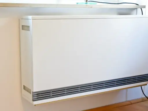 Ein weißer Nachtspeicherheizkörper an einer Wand. Der Austausch von Nachtspeicherheizungen ist Pflicht, um Energie zu sparen.