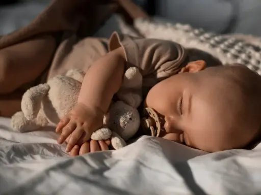 Bambino addormentato con peluche e ciuccio, forse in una fase di regressione del sonno.