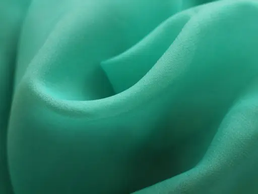 Detaljerad bild av turkos polyestertyg som visar hur tillverkas polyester genom vävning.