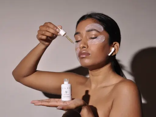Donna applica siero con contagocce, ha maschera occhi e auricolari. Chissà ogni quanto maschera occhi per un viso radioso.