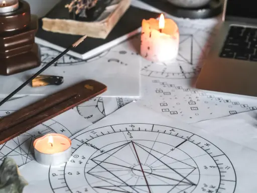 Świece i kadzidełka tworzą mistyczną atmosferę wokół kart astrologicznych. 11 dom astrologia w centrum uwagi.