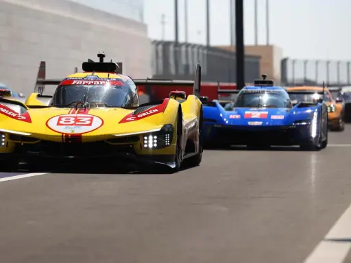 Gelber Ferrari Le Mans Hypercar mit Startnummer 83 und blauer Konkurrenz auf der Rennstrecke.