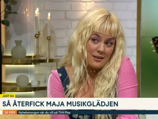 Maja Francis, med sitt blonda hår och rosa tröja, pratar om hur hon återfick sin musikglädje. En gitarr syns i bakgrunden.