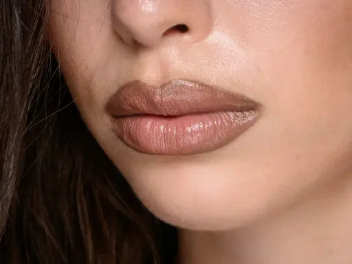 Labbra carnose e lucide, con un effetto naturale per ingrandire le labbra, evidenziate da un rossetto nude.