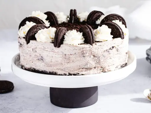 Pyszny sernik oreo na zimno, udekorowany bitą śmietaną i ciasteczkami. Idealny deser na upalne dni.