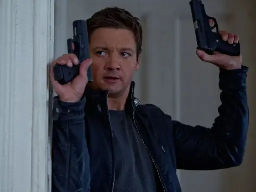 Jeremy Renner som Aaron Cross i rollistan i Jason Bourne-filmerna, redo för action med två pistoler.