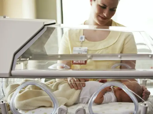 Pielęgniarka opiekuje się dzieckiem urodzonym w 32 tygodniu ciąży w inkubatorze.
