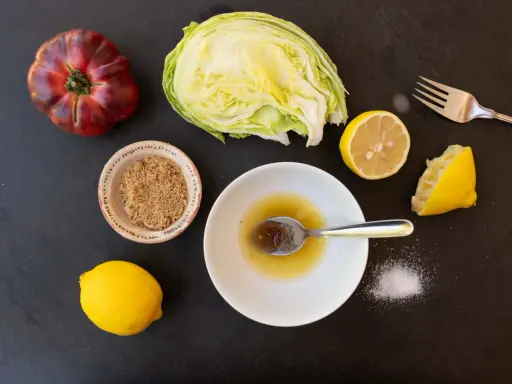 Zutaten für ein einfaches salatdressing mit zitrone und zucker: Eisbergsalat, Tomate, Zitronen, brauner Zucker und Salz.