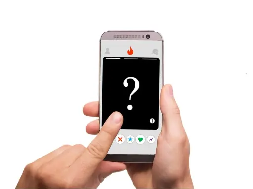 Dłoń trzyma smartfon z aplikacją randkową. Na ekranie znak zapytania i ikony: X, gwiazdka, serce, błyskawica – typowe oznaczenia na Tinderze.