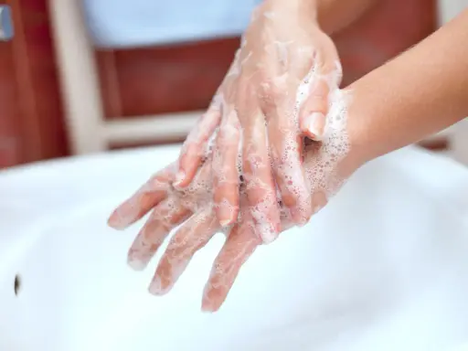 Mani insaponate che dimostrano come è fatto il sapone, creando una schiuma soffice per pulire.