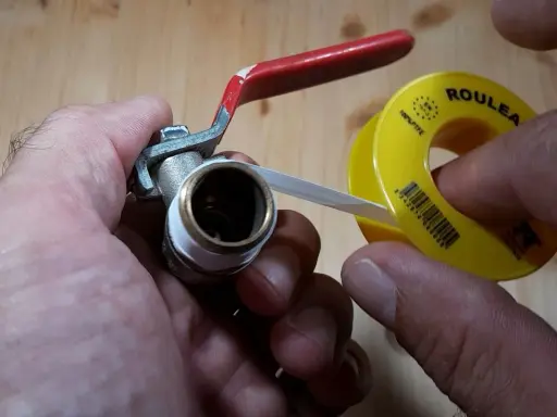 Main tenant une vanne, il applique du ruban de téflon pour assurer une étanchéité parfaite.