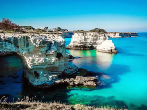 Scogliere bianche e mare turchese, un sogno per i mete puglia estate. L'arco naturale invita a scoprire le acque cristalline.