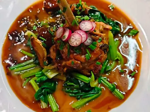 Un plat savoureux, un os de viande braisé dans une sauce riche, garni de radis et de légumes verts. Un aperçu des spécialités parisiennes.
