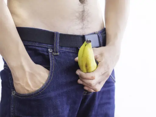Mężczyzna w dżinsach trzyma banana, sugerując jelqing efekty.