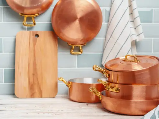 Utensilios de cobre apilados y colgados, listos para aprender como limpiar el cobre y mantenerlos brillantes.