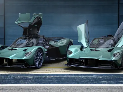 Zwei Aston Martin Valkyrie Spider in Mintgrün mit geöffneten Flügeltüren stehen nebeneinander.