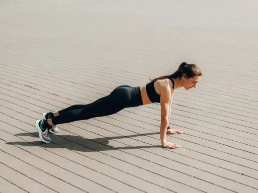 Femme en tenue de sport faisant une planche, un excellent exercice pour perdre du ventre.